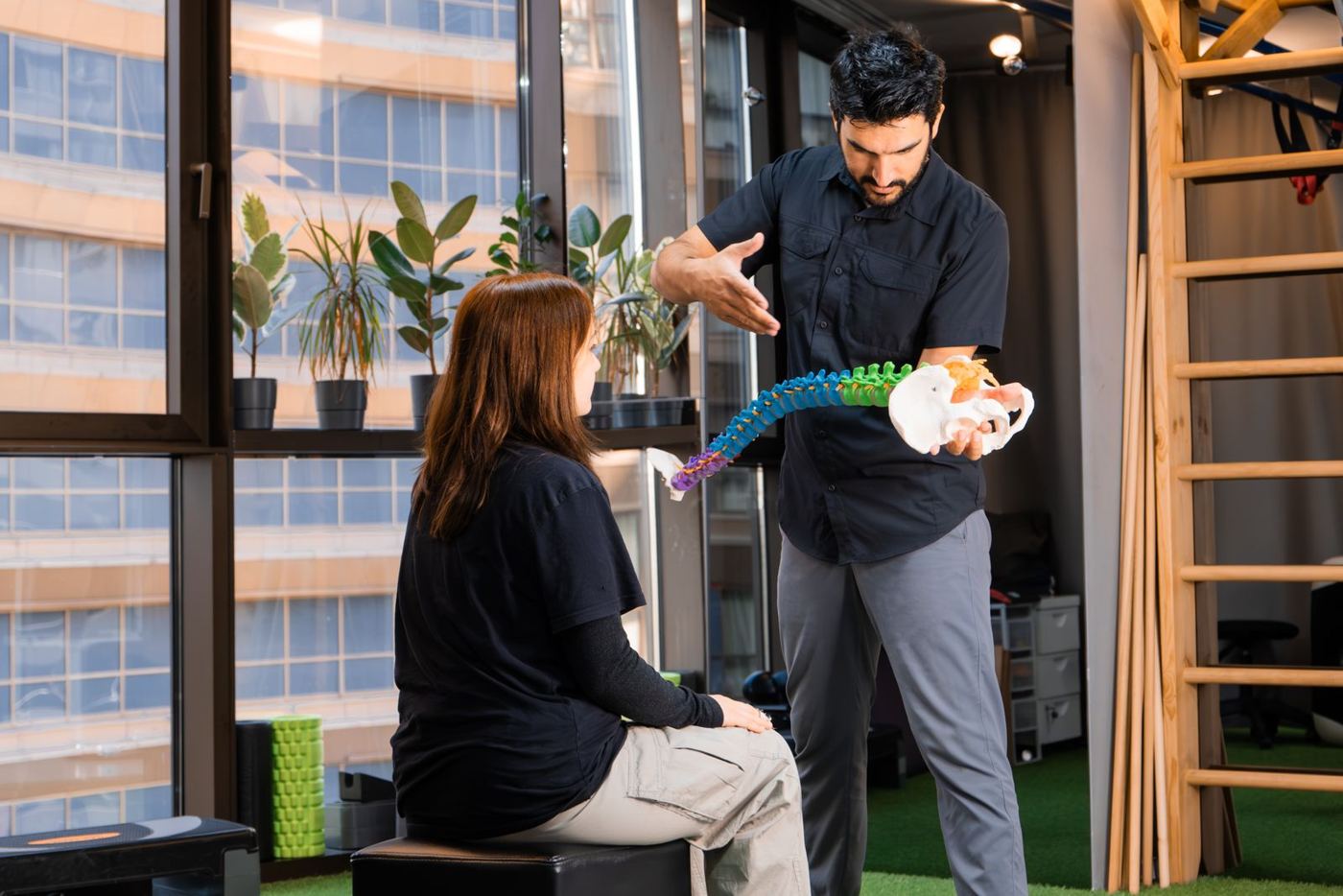 Chiropractor using a spine model to explain cervical anatomy to a patient