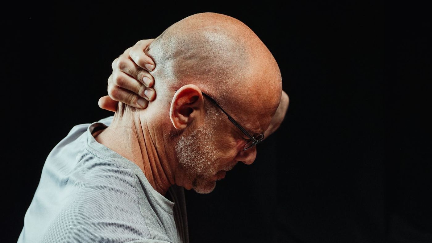 Man holding his neck, illustrating delayed whiplash symptoms